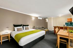 a hotel room with a bed, table, chair and a lamp at Quest Waterfront in Hobart