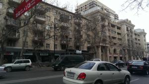 un coche blanco conduciendo por una calle de la ciudad con edificios en Izmir Apartment, en Baku