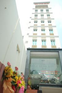 un grand bâtiment blanc avec des fleurs dans une fenêtre dans l'établissement Golf Star Hotel, à Hô-Chi-Minh-Ville