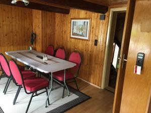 a dining room with a table and red chairs at Drei Linden Harz in Wolfenbüttel