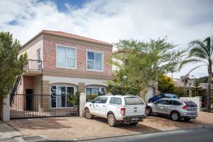 zwei Autos, die vor einem Haus geparkt sind in der Unterkunft Rustic Retreat Apartment in Durbanville in Durbanville