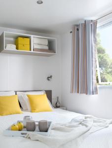 a bedroom with a white bed with yellow pillows at Le Goh Velin in Saint-Gildas-de-Rhuys