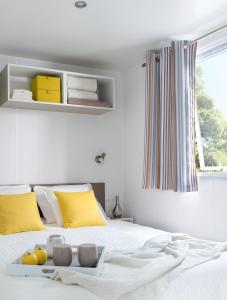 ein Schlafzimmer mit einem weißen Bett und gelben Kissen in der Unterkunft Le Goh Velin in Saint-Gildas-de-Rhuys