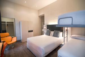 a hotel room with a bed and a chair at Petit Palace Canalejas Sevilla in Seville