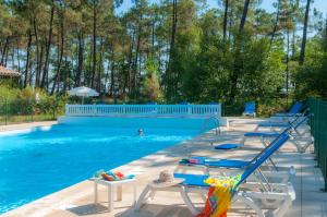 una piscina con sillas y una persona en el agua en Résidence Goélia La Marina de Talaris, en Lacanau