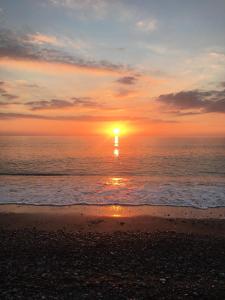 einen Sonnenuntergang am Strand mit dem Meer in der Unterkunft Kings Avenue - Natalia's Apt in Paphos City