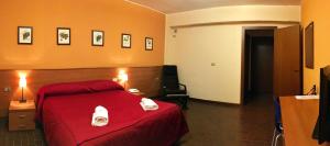a bedroom with a red bed with towels on it at Hotel Forum in Rozzano