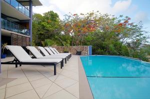 a row of chairs sitting next to a swimming pool at at Waterfront Whitsunday Retreat - Adults Only in Airlie Beach
