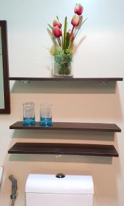 ein Regal über einer Spüle mit zwei Gläsern und Blumen in der Unterkunft Hermione's Haven at Horizon 101 Cebu in Cebu City