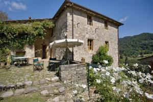 a stone building with a table and an umbrella at Villa Bottino in San Martino in Freddana