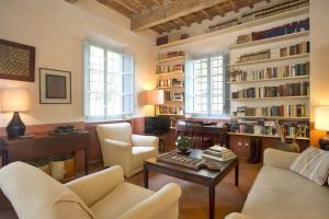 a living room with white furniture and bookshelves at Villa La Macchietta in Monsagrati