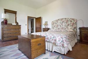 a bedroom with a bed with a floral bedspread and a dresser at La Fonte by Salogi Villas in Palaia +30 photos
