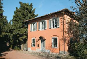 an orange house with white windows and a tree at Villa La Macchietta in Monsagrati