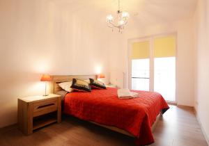 a bedroom with a bed with a red blanket and a chandelier at Apartament Polanki Park-kryty basen in Kołobrzeg