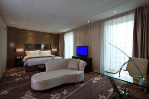 a hotel room with a bed and a couch and a television at The Jade Boutique Hotel in Wuhan
