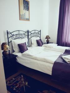 a bedroom with a large bed with white sheets and pillows at Pensiunea Byblos in Piatra Neamţ