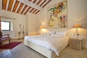 a bedroom with a white bed and a large painting on the wall at La Maccinaia by Salogi Villas in Monte Benichi +37 photos