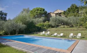 a swimming pool in a yard with chairs and a house at Villa La Loggia in Collodi