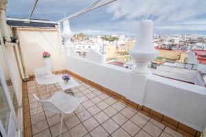 uma varanda com cadeiras brancas e vista para a cidade em Petit Palace Canalejas Sevilla em Sevilha