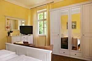 1 dormitorio con 1 cama, TV y espejo en Rhön Hotel Waldcafé St. Georg en Staatsbad Brückenau