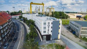 a white building with a crane on top of it at Vulcan Hotel in Szczecin
