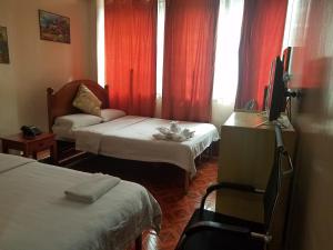 een kamer met 2 bedden en een tv. bij Hotel 45 Extension in Baguio