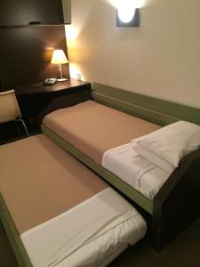 two beds in a room with a desk and a lamp at At Home Appart Hotel in Toulouse