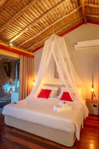 a bedroom with a white bed with a mosquito net at Secret Garden Beach Resort in Bangrak Beach