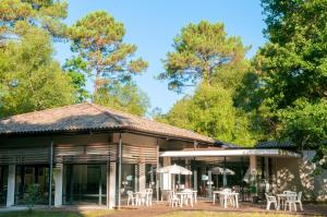 un edificio con mesas, sombrillas y árboles en Résidence Goélia La Marina de Talaris, en Lacanau