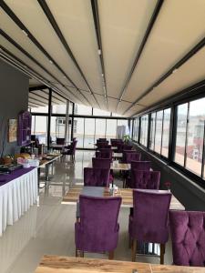 a restaurant with purple chairs and tables and windows at Hotel Iz in Izmir