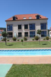 a house with a swimming pool in front of a building at Grupoele3 Edificio Mar Langosteira in Fisterra