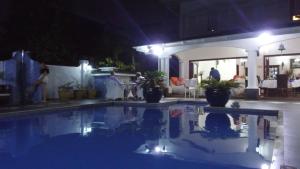 a swimming pool at night with people sitting around it at Le Bonheur Villa in Victoria
