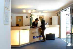 Dos mujeres están de pie en el mostrador del baño del hotel en Hotel Bettina garni, en Günzburg