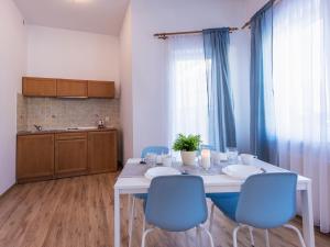 a kitchen with a white table and blue chairs at VacationClub - Olymp Apartment 503 in Kołobrzeg