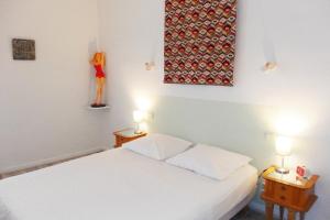 a bedroom with a white bed and two tables with lamps at La Maison de Thaïs in Arles