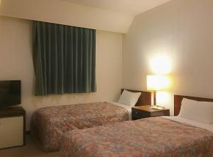a hotel room with two beds and a television at Marroad Inn Kumagaya in Kumagaya