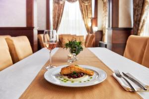 a plate of food on a table with a glass of wine at Platinum Image Hotel in Elin Pelin