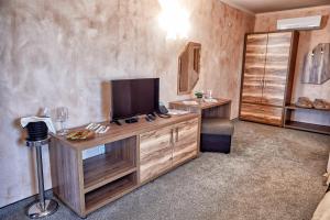 a room with a tv on a wooden entertainment center at Platinum Image Hotel in Elin Pelin