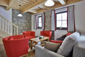 a living room with red chairs and a couch at Rezort Gothal Chalupy in Donovaly