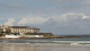 a building on the shore of a beach with the ocean at Spanish Cove Holiday Homes Sleeps 5 by Trident Holiday Homes in Kilkee