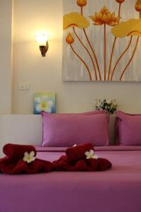 
a bed with a pink blanket and pillows on it at Nimmanoradee Resort - SHA PLUS Certified in Ko Samed
