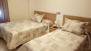 dwa łóżka siedzące obok siebie w sypialni w obiekcie Hostal Tilos w Maladze