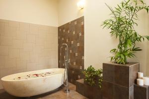 a bath tub in a bathroom with two plants at Old Kent Estates & Spa, Coorg in Suntikoppa