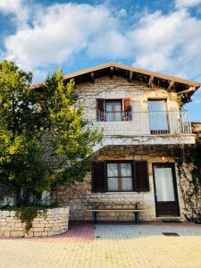 un antiguo edificio de piedra con balcón y un árbol en Agriturismo Amicizia, en Cassano delle Murge