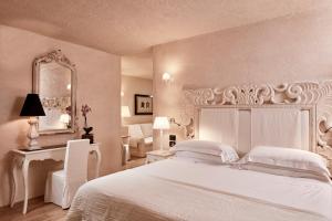 a white bedroom with a large white bed and a desk at La Villa Del Re - Adults Only - Small Luxury Hotels of the World in Castiadas