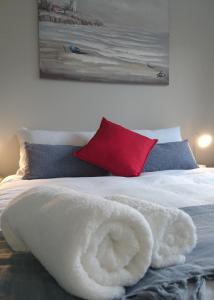 a bed with a white blanket and a red pillow at Hamilton Garden Suites in Parklands