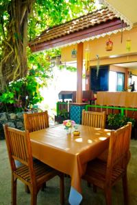 een houten tafel met twee stoelen en een tafel met bloemen erop bij Baan Karon Hill Phuket Resort in Karon Beach