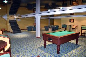 a pool table in the middle of a room with chairs at Hotel Le Pole Europeen in Aubange