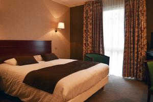 a bedroom with a large bed and a window at Hotel Le Pole Europeen in Aubange
