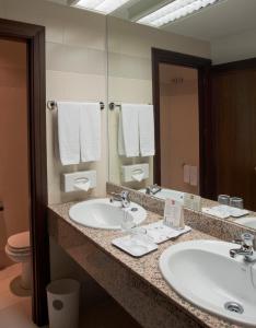 a bathroom with two sinks and a large mirror at Hotel Riu Fluviá in Olot